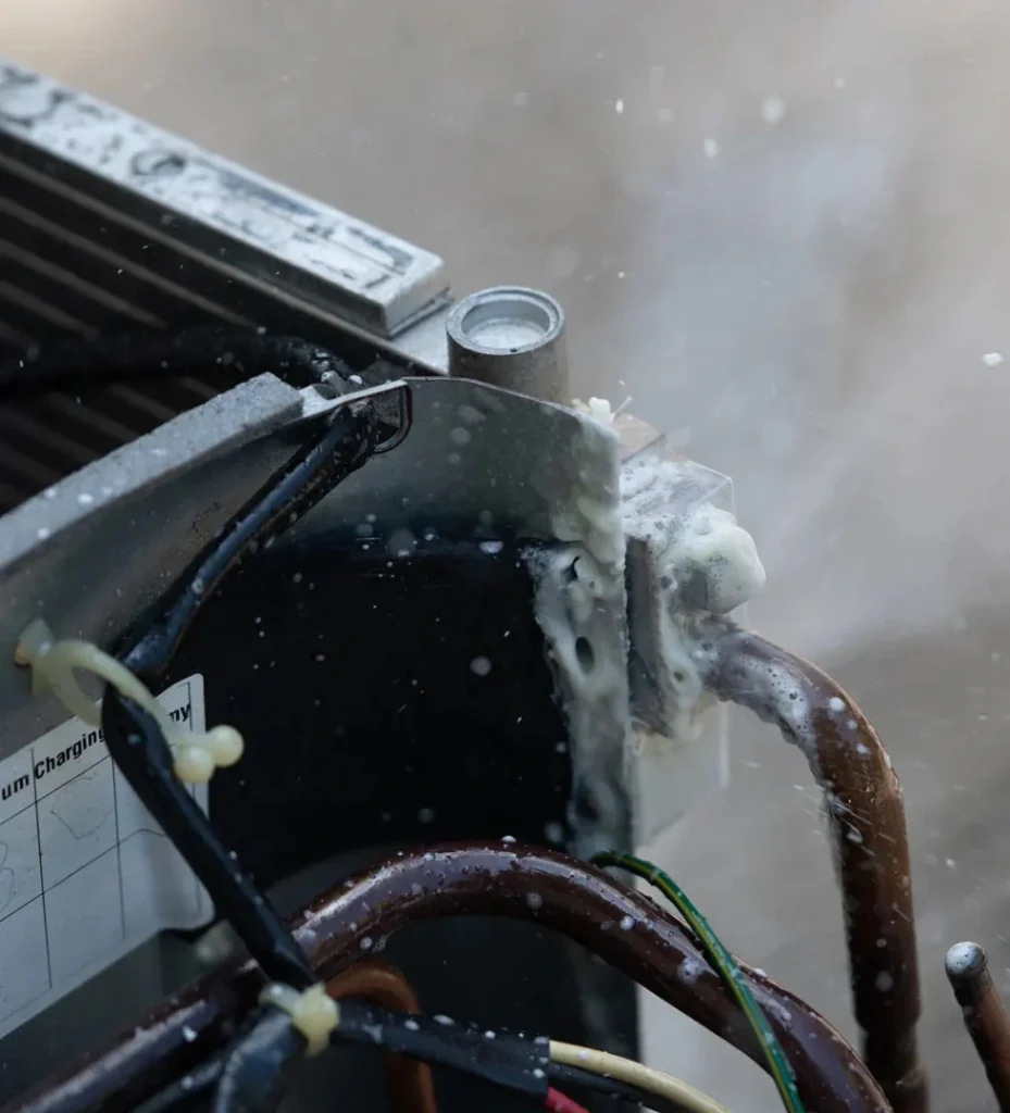 Close-up of an air conditioning unit showing a refrigerant leak, with foam escaping from the pipes, highlighting a common problem that can affect cooling performance and efficiency.